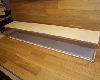 May include: A long, rectangular display case made of wood and clear acrylic. The case has a light wood finish and a clear acrylic front and sides. The case is sitting on a wooden surface.