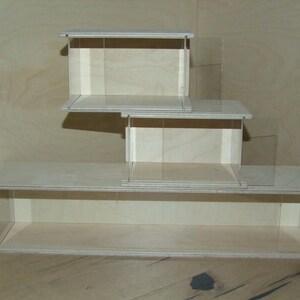 May include: Three wooden display cases stacked on top of each other. The cases are made of light wood and have clear glass sides. The cases are empty.