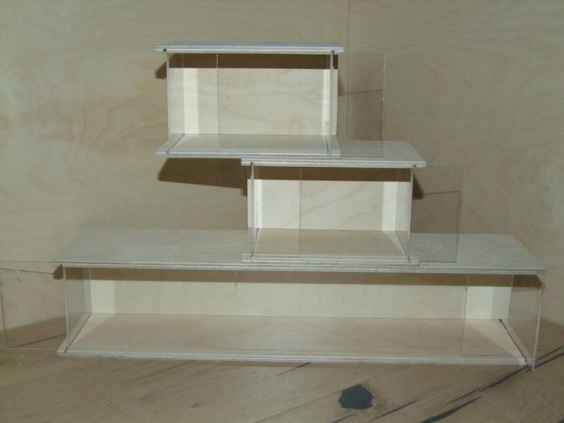 May include: Three wooden display cases stacked on top of each other. The cases are made of light wood and have clear glass sides. The cases are empty.