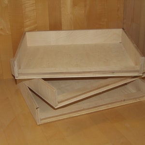 Könnte beinhalten: Zwei Holztabletts, die übereinander gestapelt sind. Die Tabletts sind aus hellem Holz und haben ein schlichtes Design.