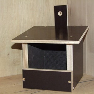 May include: A dark brown wooden birdhouse with a small opening for birds to enter. The birdhouse has a flat roof and a small perch on the front.