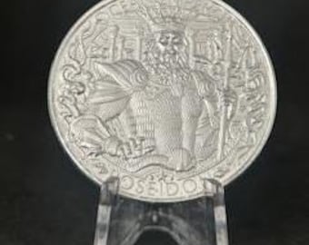 May include: A silver coin featuring a detailed relief of a bearded figure in regal attire, holding a staff. The coin is displayed on a clear plastic stand against a dark background. The coin's design includes the name "POSEIDON" and other text.