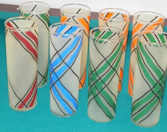 Pode incluir: Conjunto de oito copos de beber de vidro transparente com acabamento fosco. Cada copo tem um padrão geométrico de cor diferente em preto, vermelho, verde, azul e laranja.
