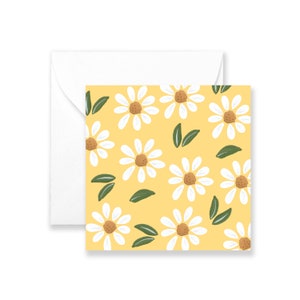 May include: A yellow card with a white border and a pattern of white daisies with brown centers and green leaves.