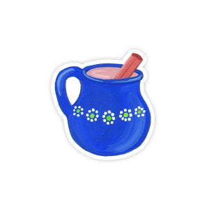 May include: A blue ceramic mug with a white and green floral design, filled with pink liquid and a cinnamon stick sticking out.