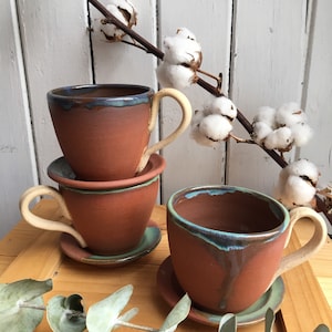 Juego de taza y platillo en cerámica de terracota roja con detalle azul