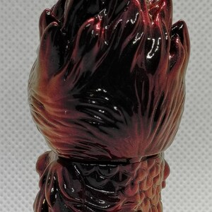 K&ouml;nnte beinhalten: Gl&auml;nzende Figur in Rot- und Braunt&ouml;nen. Die Figur hat einen stacheligen Kopf und einen strukturierten K&ouml;rper. Das Design deutet auf ein Sammlerst&uuml;ck mit Fantasy- oder Monstermotiven hin. Die Figur ist klein und abgerundet.