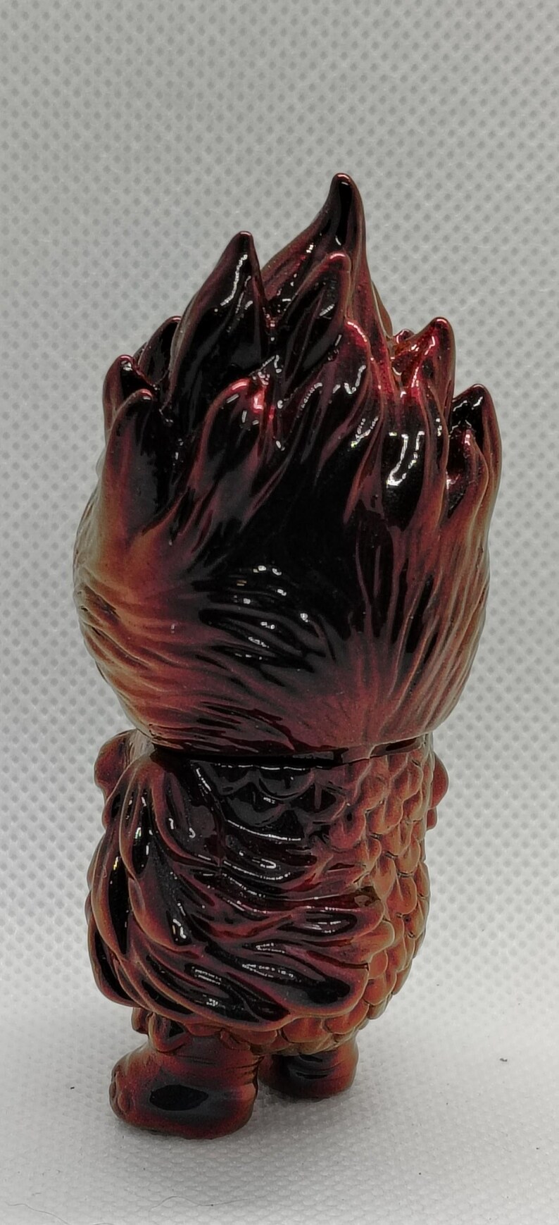 K&ouml;nnte beinhalten: Gl&auml;nzende Figur in Rot- und Braunt&ouml;nen. Die Figur hat einen stacheligen Kopf und einen strukturierten K&ouml;rper. Das Design deutet auf ein Sammlerst&uuml;ck mit Fantasy- oder Monstermotiven hin. Die Figur ist klein und abgerundet.