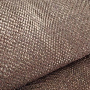 Op de afbeelding: Close-up van een getextureerd, bruin leermateriaal met een schubbenachtig patroon. Het leer heeft een licht glanzende uitstraling en een natuurlijke, organische textuur. Het materiaal is gevouwen en onthult de onderkant.