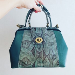 May include: A green leather handbag with a snakeskin pattern and a gold clasp.