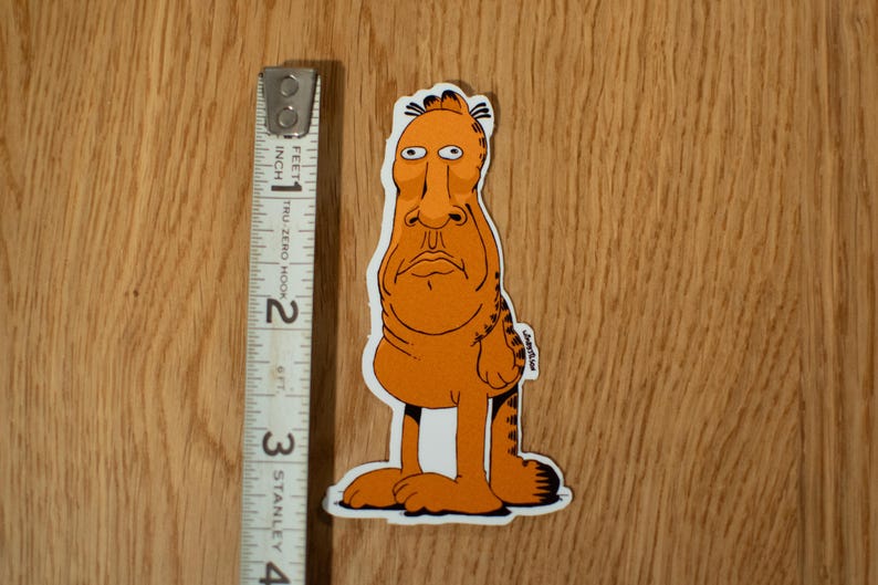K&ouml;nnte beinhalten: Ein orangefarbener und schwarzer Comic-Charakter-Aufkleber mit einem langen Gesicht und langen Beinen. Der Charakter steht mit seinen Armen an den Seiten.