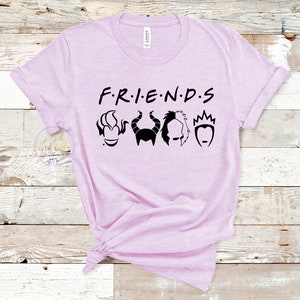 Puede incluir: Una camiseta de color morado claro con el texto "F.R.I.E.N.D.S" en negro. Debajo del texto hay cinco siluetas negras de villanos de Disney: &Uacute;rsula, Mal&eacute;fica, Cruella de Vil, la Reina Malvada y la Reina de Corazones.