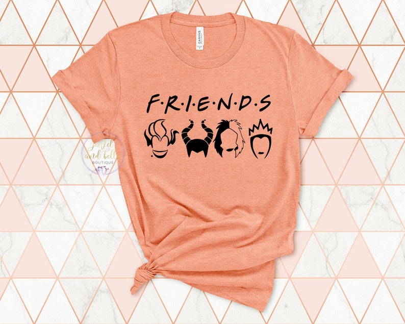 Puede incluir: Camiseta naranja con el texto "F.R.I.E.N.D.S." en negro. El texto est&aacute; estilizado para parecerse al t&iacute;tulo de la serie de televisi&oacute;n "Friends". Hay cinco siluetas negras de villanos de Disney debajo del texto.