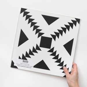 May include: Black and white geometric patterned floor tile with a textured surface. The tile features a repeating pattern of triangles and squares. The tile is labelled "Parla Floor Tiles" and "Create your world".