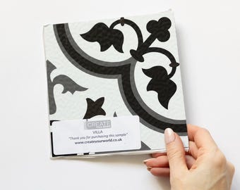 Puede incluir: Muestra de baldosa cuadrada con un diseño floral en blanco y negro. La baldosa tiene un fondo claro, un borde gris oscuro y detalles florales negros. El texto "VILLA" y un mensaje de agradecimiento son visibles.