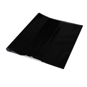 K&ouml;nnte beinhalten: Eine Rolle schwarzes, gl&auml;nzendes, selbstklebendes Vinylpapier. Das Papier ist aufgerollt und das Ende ist sichtbar.
