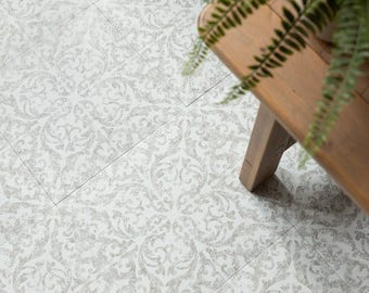 May include: Overhead view of a floor with a repeating, ornate, light gray and white damask pattern. The floor is made of rectangular tiles. A small, wooden bench with a plant on top is in the upper right corner.