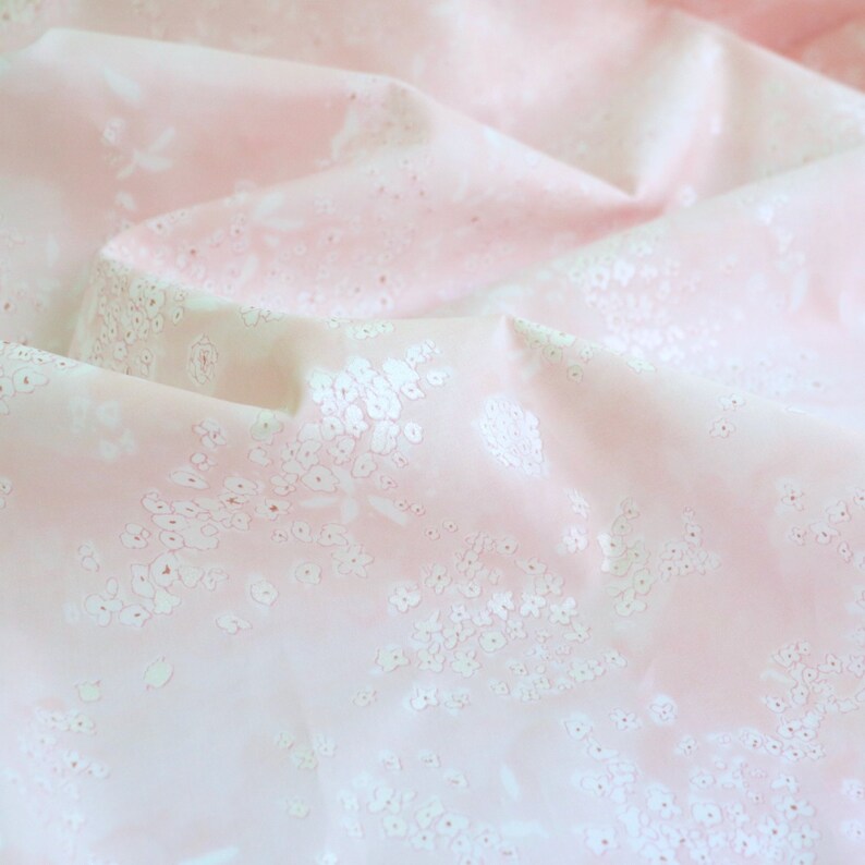 Pode incluir: Tecido rosa claro com um delicado padr&atilde;o floral. O tecido &eacute; drapeado, criando dobras e sombras que real&ccedil;am o design. Pequenos motivos florais brancos est&atilde;o espalhados sobre o fundo rosa.