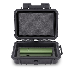 May include: An open black hard case with a green electronic device inside. The device has a small white X on it. The case has a foam insert and is designed to protect the device. The case is open and ready for use.