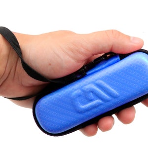 K&ouml;nnte beinhalten: Eine blaue Rei&szlig;verschlusstasche mit einem schwarzen Riemen. Die Tasche hat eine strukturierte Oberfl&auml;che und ein Logo auf der Vorderseite.