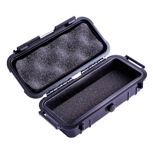 May include: A black plastic case with a foam interior. The case is open and the foam is visible. The case has a latch and a small knob on the side.