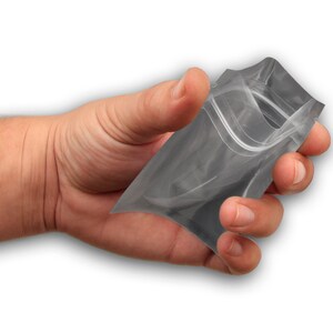 May include: A clear plastic stand-up pouch with a zipper closure. The pouch is being held in a hand.