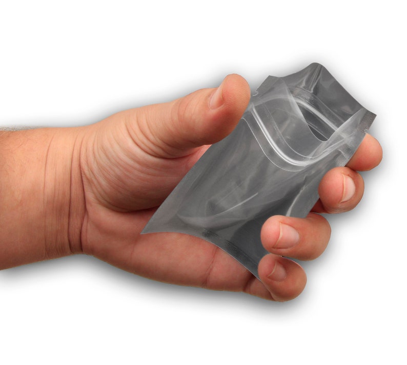 May include: A clear plastic stand-up pouch with a zipper closure. The pouch is being held in a hand.