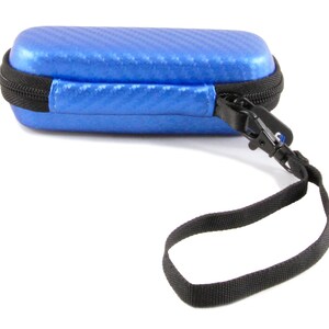 K&ouml;nnte beinhalten: Ein blaues Rei&szlig;verschluss-Etui mit einem schwarzen Riemen. Das Etui hat ein Karbonfaser-Muster.