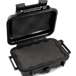 May include: A black waterproof storage case with a hinged lid and a foam interior. The case has a latch on the side and a small knob on the front.