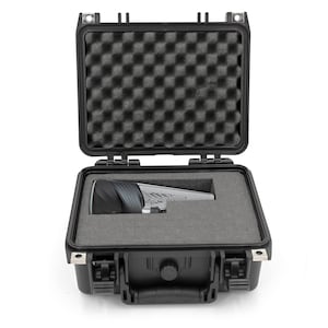 May include: Open black hard case with a gray foam interior. Inside the case is a silver and black object. The case has a handle and secure latches. The top of the case is open, revealing the foam padding.