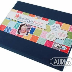 May include: A blue box with a colourful patchwork design featuring a variety of fabrics. The box is labelled "Bee Happy Aurifil" and includes the text "Limited Edition by Lori Holt of Bee in my Bonnet".