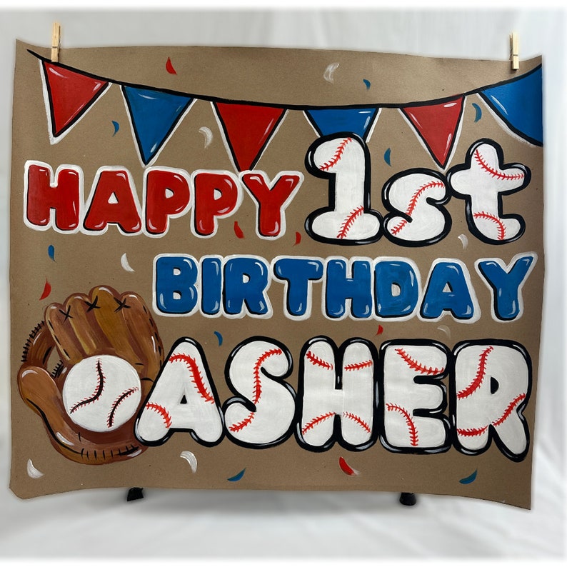May include: A brown banner with the words "HAPPY 1st BIRTHDAY ASHER" in red and blue bubble letters, with baseball-themed accents. A baseball glove and ball are on the left. Red and blue pennants and confetti complete the design.