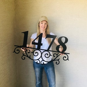 May include: Black metal house number sign with a decorative scroll design. The sign displays the number 1478.