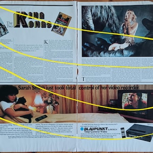 Op de afbeelding: Een dubbele pagina uit een vintage krant met filmadvertenties en artikelen. De kop luidt "King Kongs", met bijbehorende beelden. Eén advertentie toont een vrouw met een kat, en een andere promoot een "Total Control Video"-apparaat.