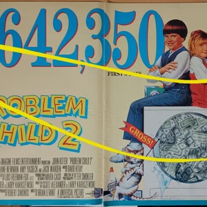 May include: Film poster for "Problem Child 2" showing two children seated on a washing machine overflowing with money. The poster displays the text "£7,642,350" in large blue numbers and the film title in yellow.