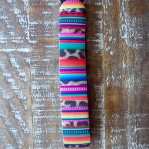May include: A colorful key chain with a multi-colored striped pattern and a leopard print design. The key chain is attached to a silver key ring.
