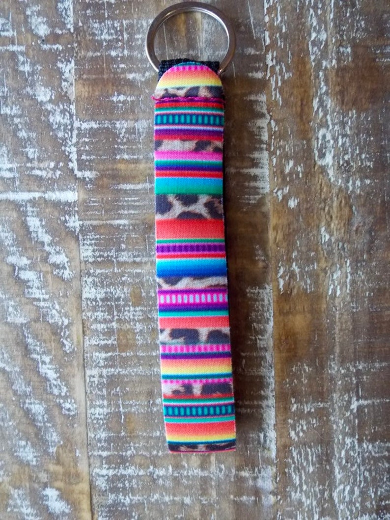 May include: A colorful key chain with a multi-colored striped pattern and a leopard print design. The key chain is attached to a silver key ring.