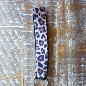 May include: A brown and black leopard print key chain with a silver key ring.