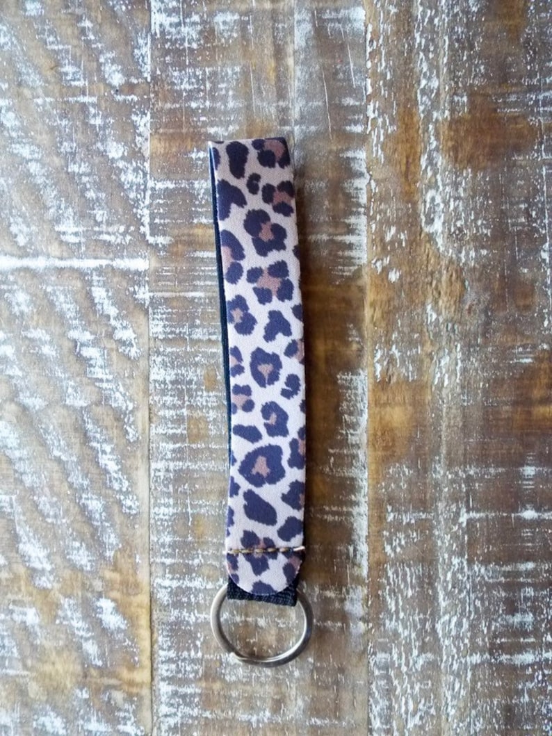 May include: A brown and black leopard print key chain with a silver key ring.