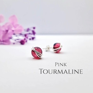 May include: Pink tourmaline gemstone earrings with silver wire wrapping. The earrings are small and delicate.