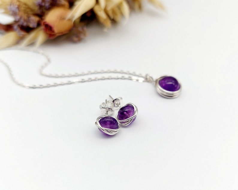 Peut inclure: Un ensemble de bijoux en am&eacute;thyste compos&eacute; d'un collier et de boucles d'oreilles. Les pierres d'am&eacute;thyste sont envelopp&eacute;es de fil d'argent et ont une couleur violet fonc&eacute;.