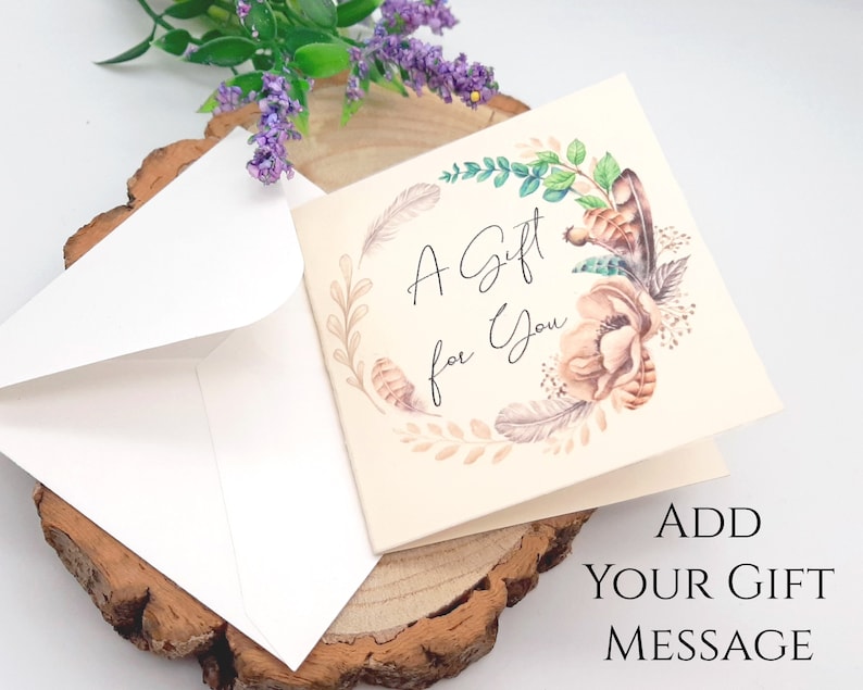 May include: A white card with a floral design and the text "A Gift for You". The card is sitting on a wooden surface with a white envelope.