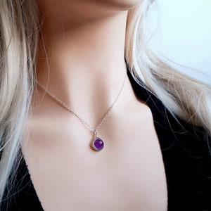 Peut inclure: Un collier en cha&icirc;ne argent avec un petit pendentif rond en pierre pr&eacute;cieuse violette.