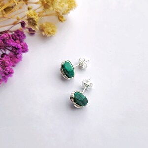 May include: A pair of silver wire wrapped earrings with green malachite stones.