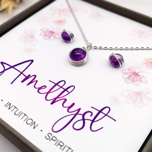 Peut inclure: Ensemble collier et boucles d'oreilles en am&eacute;thyste dans un coffret cadeau. Les bijoux pr&eacute;sentent des pierres d'am&eacute;thyste violettes envelopp&eacute;es de fil d'argent. La bo&icirc;te est orn&eacute;e d'un motif floral et du texte "Am&eacute;thyste" en &eacute;criture violette. Le texte ci-dessous indique "Cr&eacute;ativit&eacute;. Intuition. Esprit."