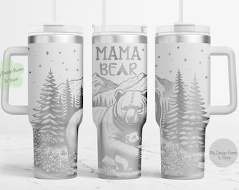 Puede incluir: Una taza de viaje de acero inoxidable blanca con una ilustración en blanco y negro de una osa madre y un osezno en un entorno de bosque. La taza tiene un asa y una pajita. El texto "Mama Bear" está impreso en la taza.