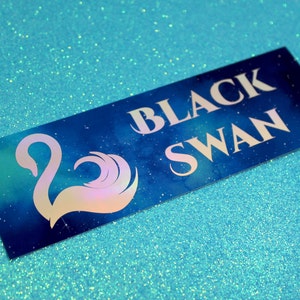 May include: A blue and green iridescent sticker with a white silhouette of a swan and the text "BLACK SWAN" in white.