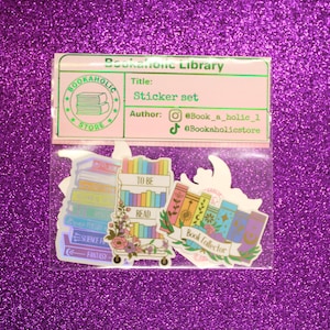 May include: A sticker set featuring colorful book-themed designs. The stickers include images of stacks of books, a book cart with the text "TO BE READ", and a "Book Collector" design. The packaging includes the text "Bookaholic Library".