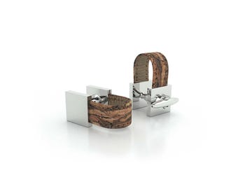 May include: A pair of silver cufflinks with a brown cork band. The cufflinks have a square shape and a simple design.