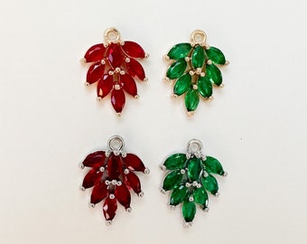May include: Four leaf-shaped charms with red and green gemstones. The charms are made of metal and have a gold finish.